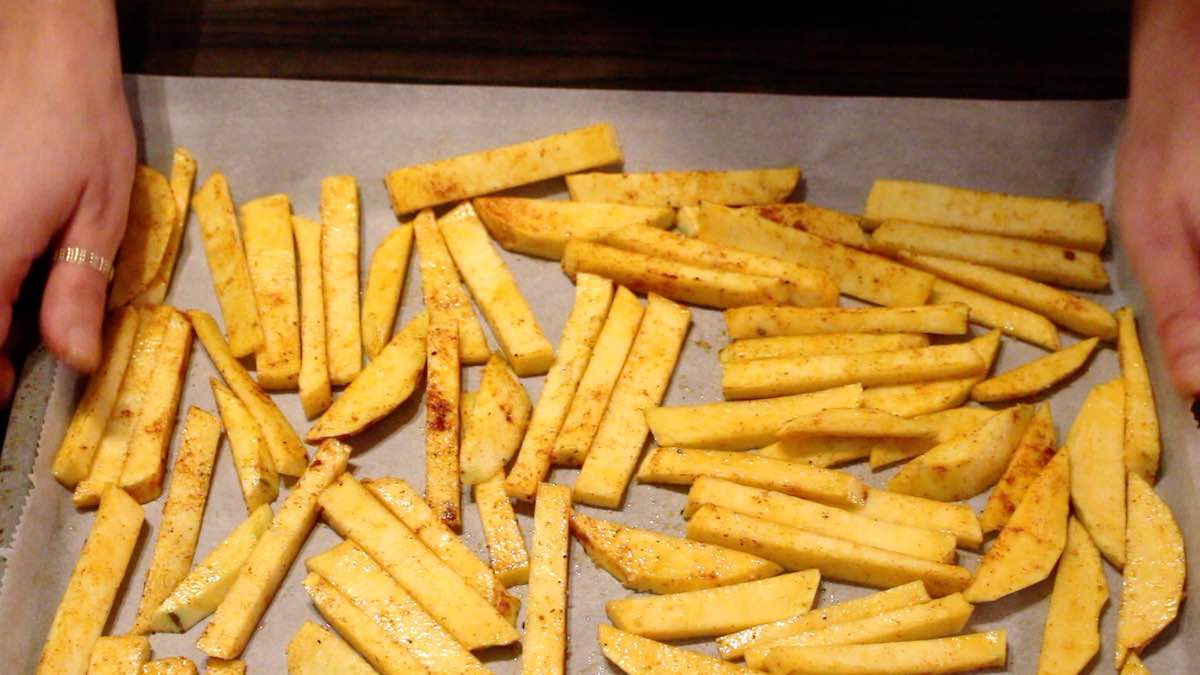 Oven-baked rutabaga fries spreading onto the baking sheet.