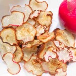 A pile of sliced radishes next to a red radish.