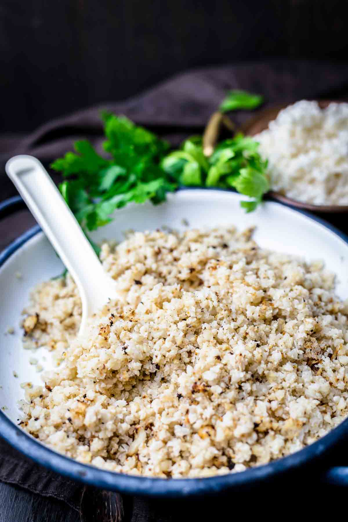 Cauliflower in a bowl with a spoon and parsley.