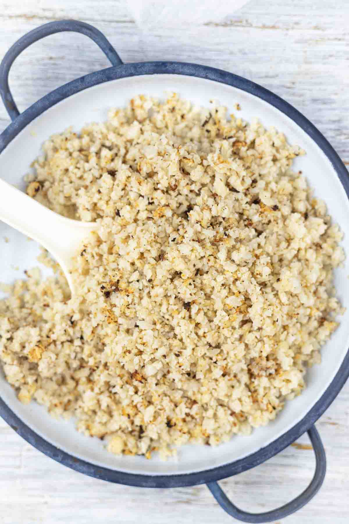 Cauliflower in a bowl with a spoon.