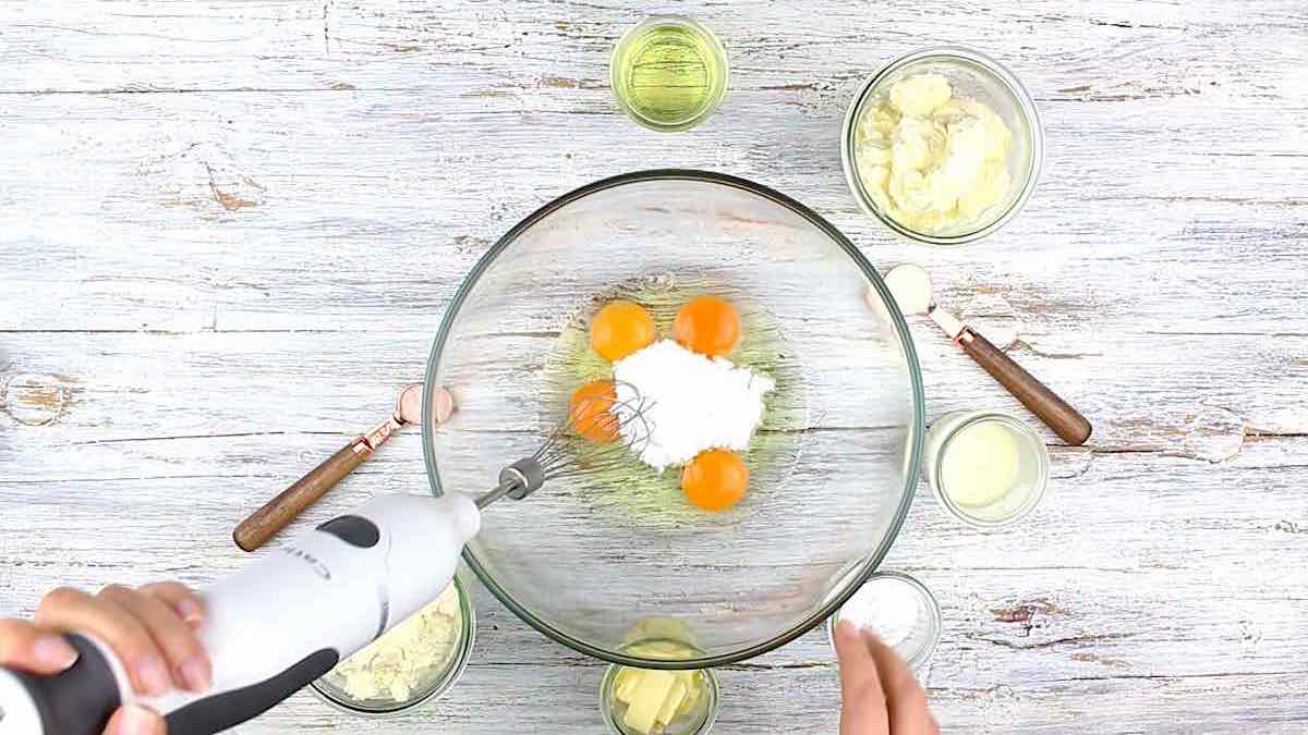 A person is mixing ingredients in a glass bowl.