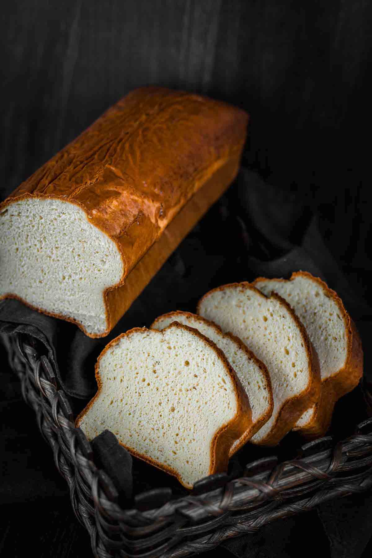 A loaf of protein bread in a basket on a black background.