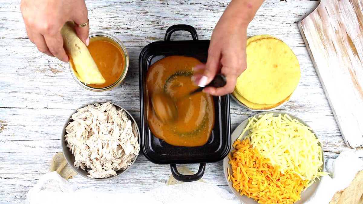 A person rolling a tortilla and putting it in a pan.