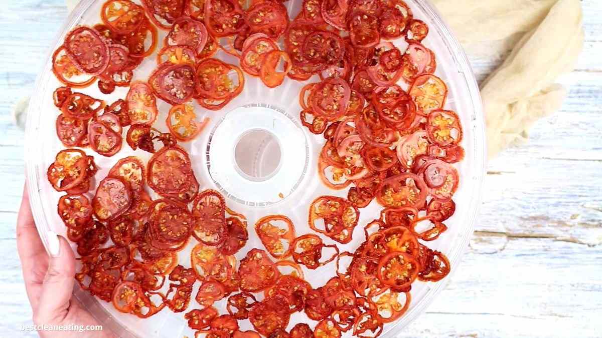 A person is holding a tray full of sliced tomatoes.