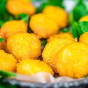 A plate of golden fried balls is garnished with fresh green parsley.