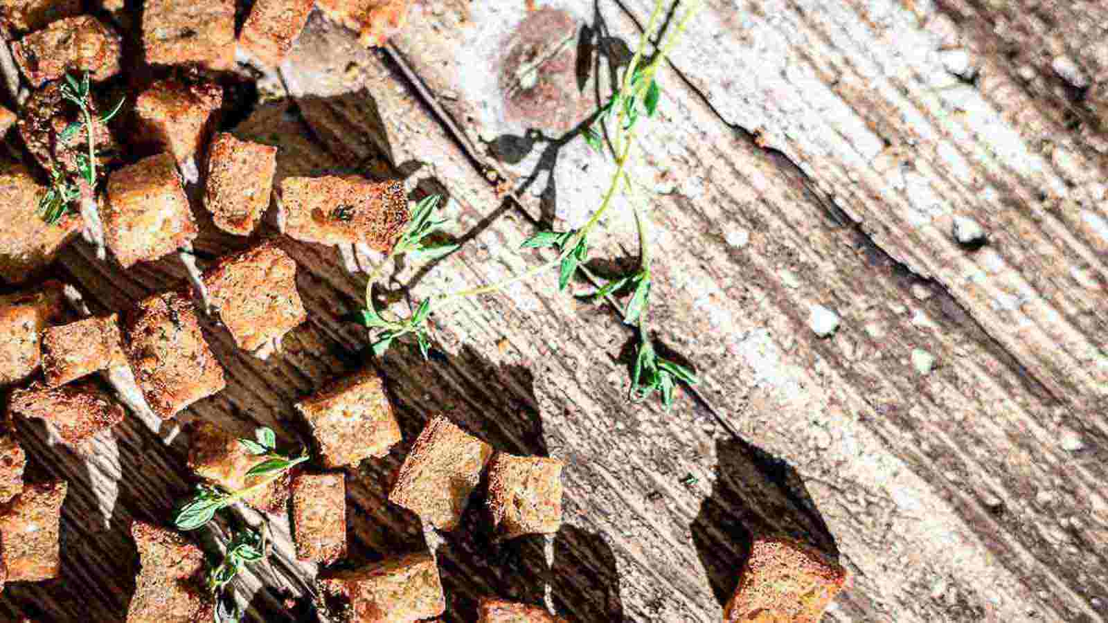 Croutons spread on a wood with herbs.
