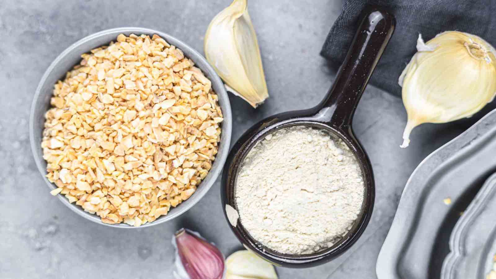 A bowl of chopped garlic and a spoonful of garlic powder.