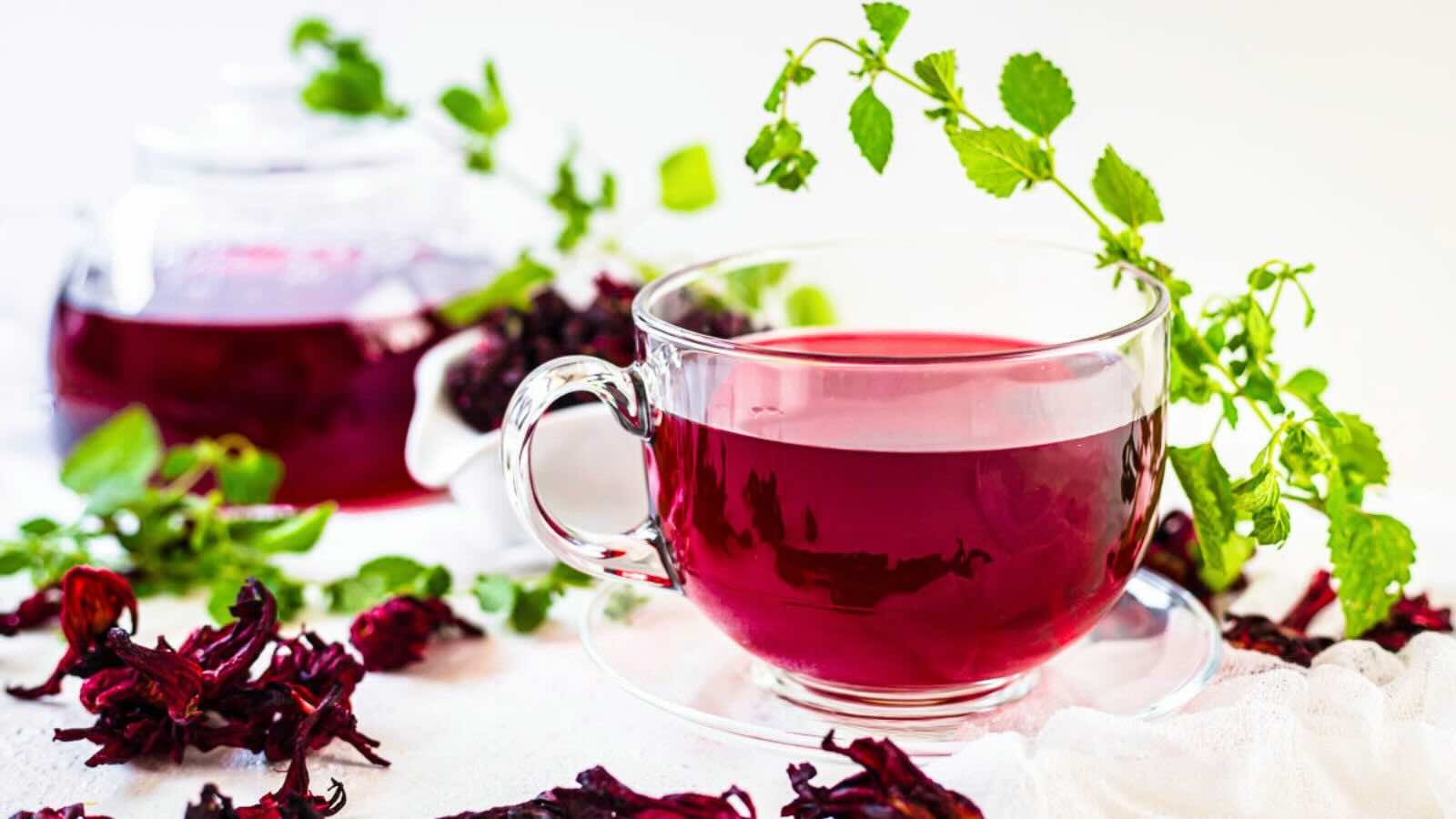 A glass cup filled with red hibiscus tea.