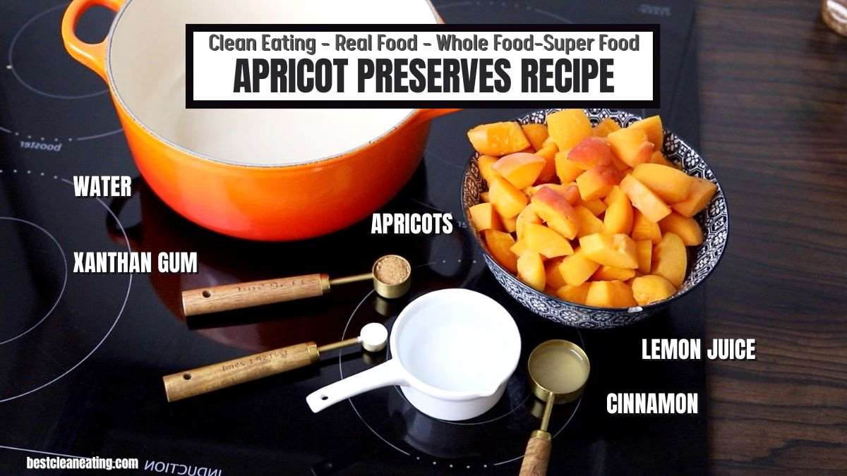 Ingredients for apricot preserves on a kitchen countertop, including a bowl of apricots, cinnamon, lemon juice, water, and xanthan gum. A pot and various measuring spoons are also visible.