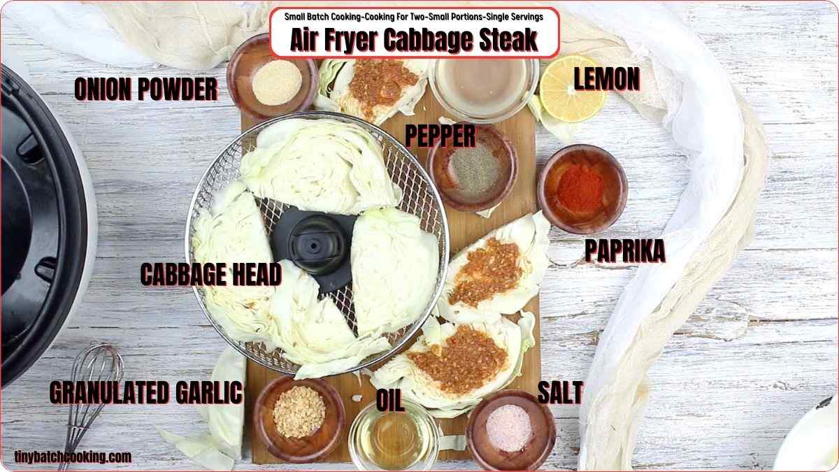 Top-view of an air fryer with cabbage slices in the basket, surrounded by labeled seasonings: onion powder, black pepper, lemon, paprika, salt, oil, granulated garlic, and a cabbage head.