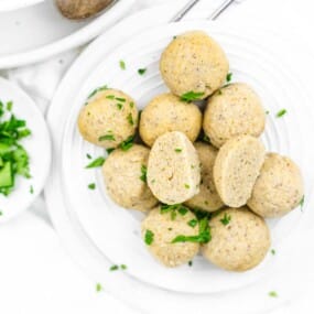 A plate of cooked dumpling balls garnished with chopped parsley.