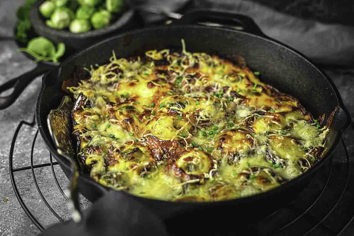 A casserole with brussel sprouts topped with cheese.