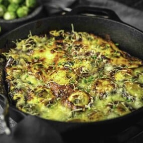 A casserole with brussel sprouts topped with cheese.