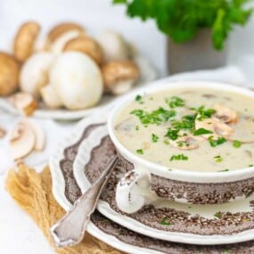 A bowl of mushroom soup garnished with chopped parsley.