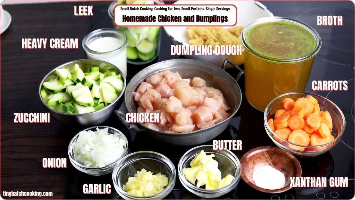 Ingredients for homemade chicken and dumplings: leek, broth, heavy cream, dumpling dough, zucchinis, diced chicken, carrots, onion, garlic, butter, and xanthan gum, arranged on a kitchen counter.