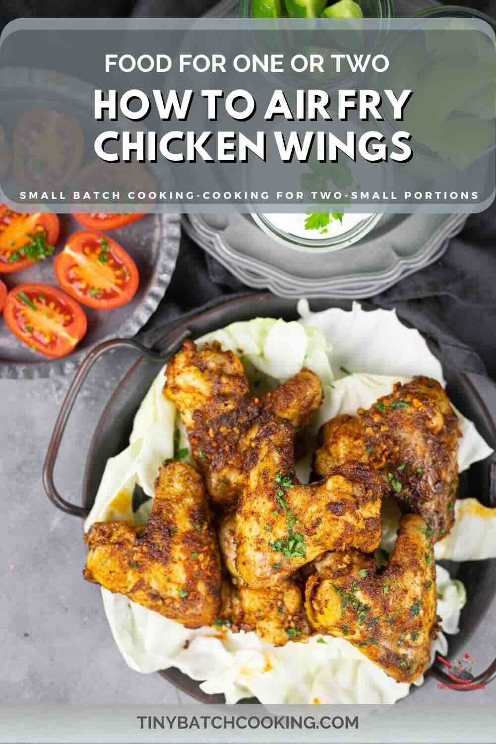 Cooked chicken wings in a pan with tomatoes and lettuce, accompanied by text that reads, "Food for One or Two: How to Air Fry Chicken Wings - Small Batch Cooking for Two - Small Portions.