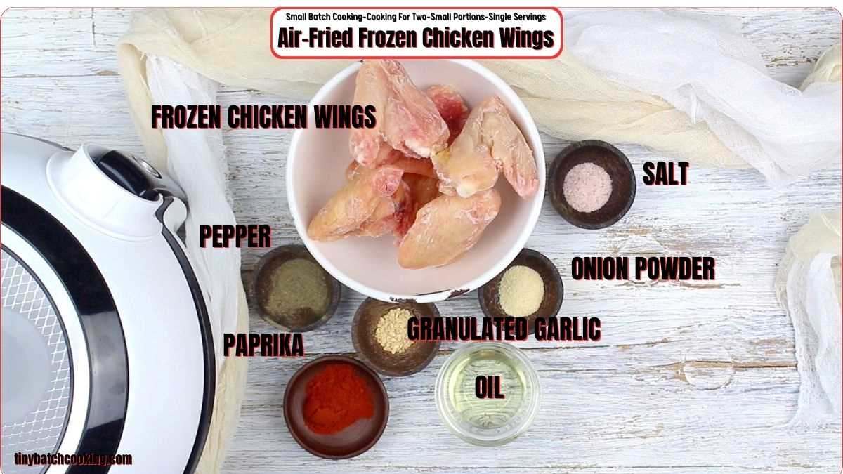 Ingredients for air-fried frozen chicken wings displayed: frozen chicken wings, salt, pepper, onion powder, paprika, granulated garlic, oil. Air fryer also visible.