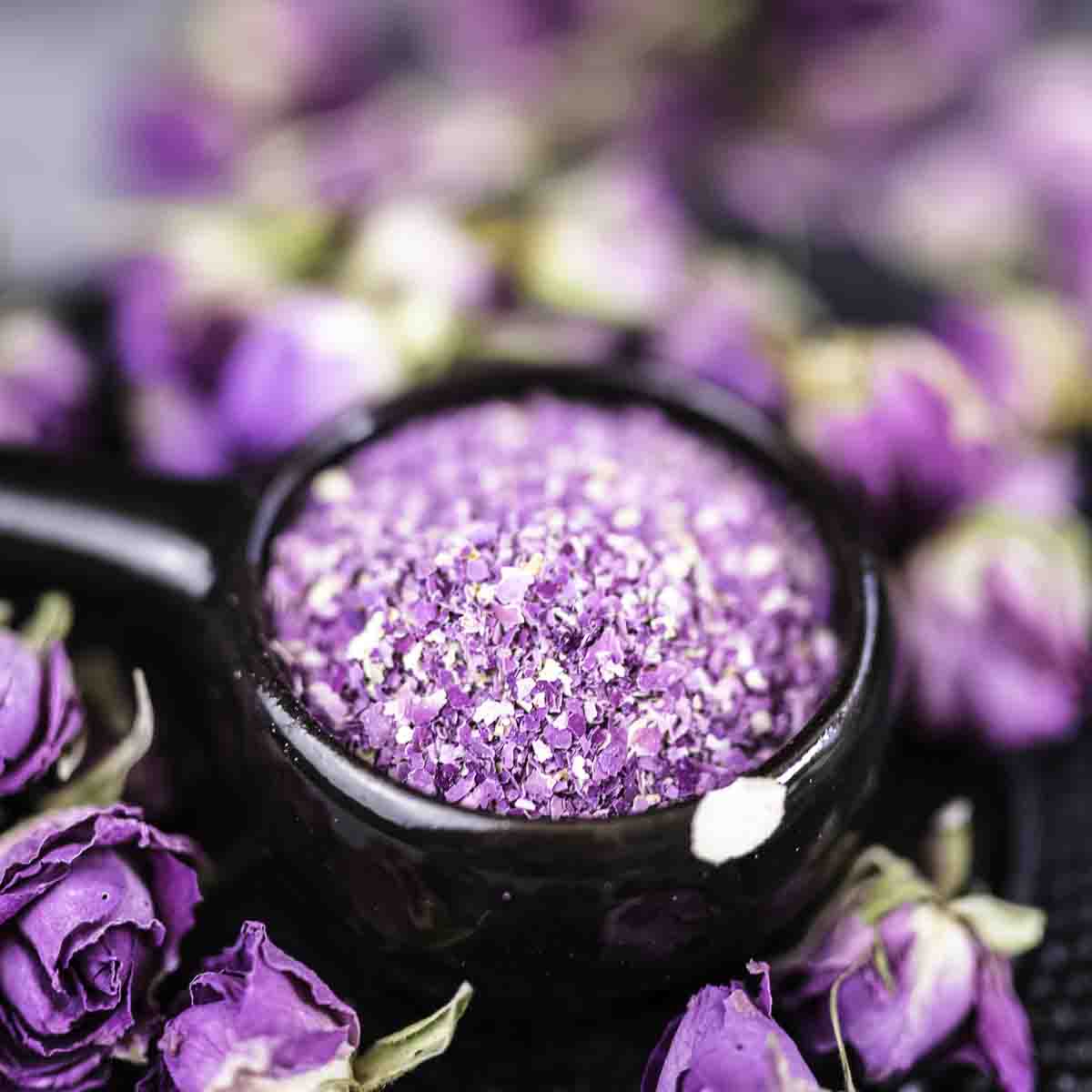 A black ceramic cup with powdered rose petals.
