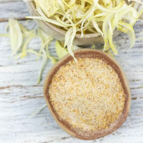 A small bowl with onion powder and a big bowl of dehydrated onion flakes at the back.