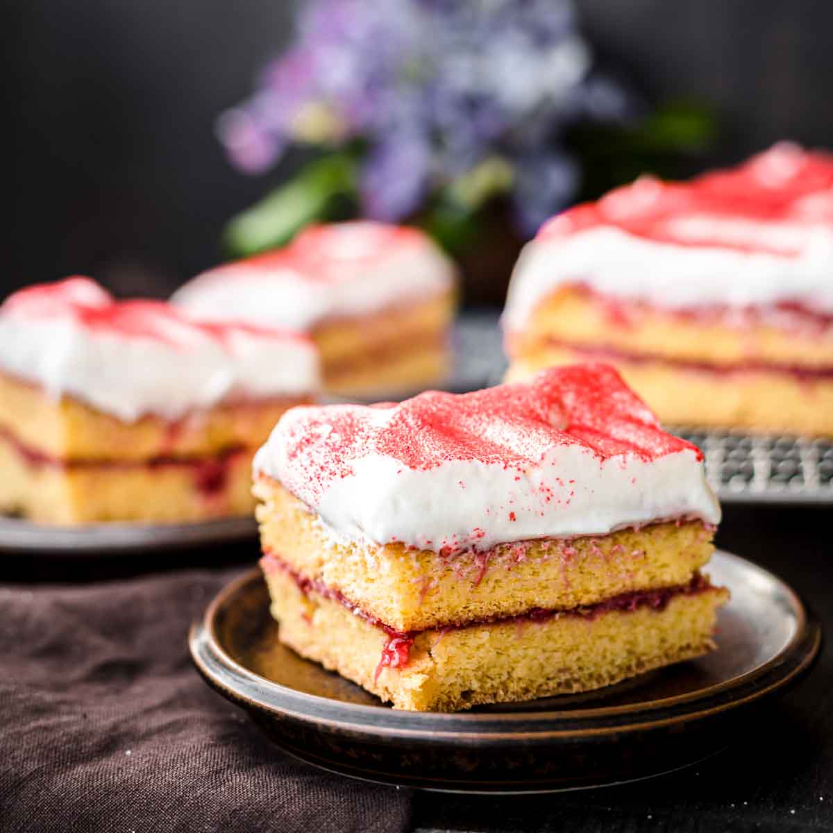 A slice of strawberry sheet cake topped with strawberry powder.