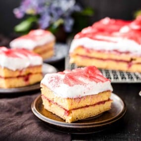 A slice of strawberry sheet cake with white frosting.