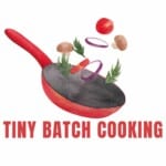 Illustration of a red frying pan with vegetables such as tomatoes, mushrooms, onions, and herbs flying above it. The text "TINY BATCH COOKING" is written below the pan in bold red letters.