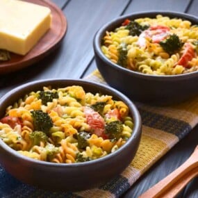 Two bowls of vegetable pasta salad with broccoli and tomatoes, perfect for enjoying the benefits of cooking for one or two people.