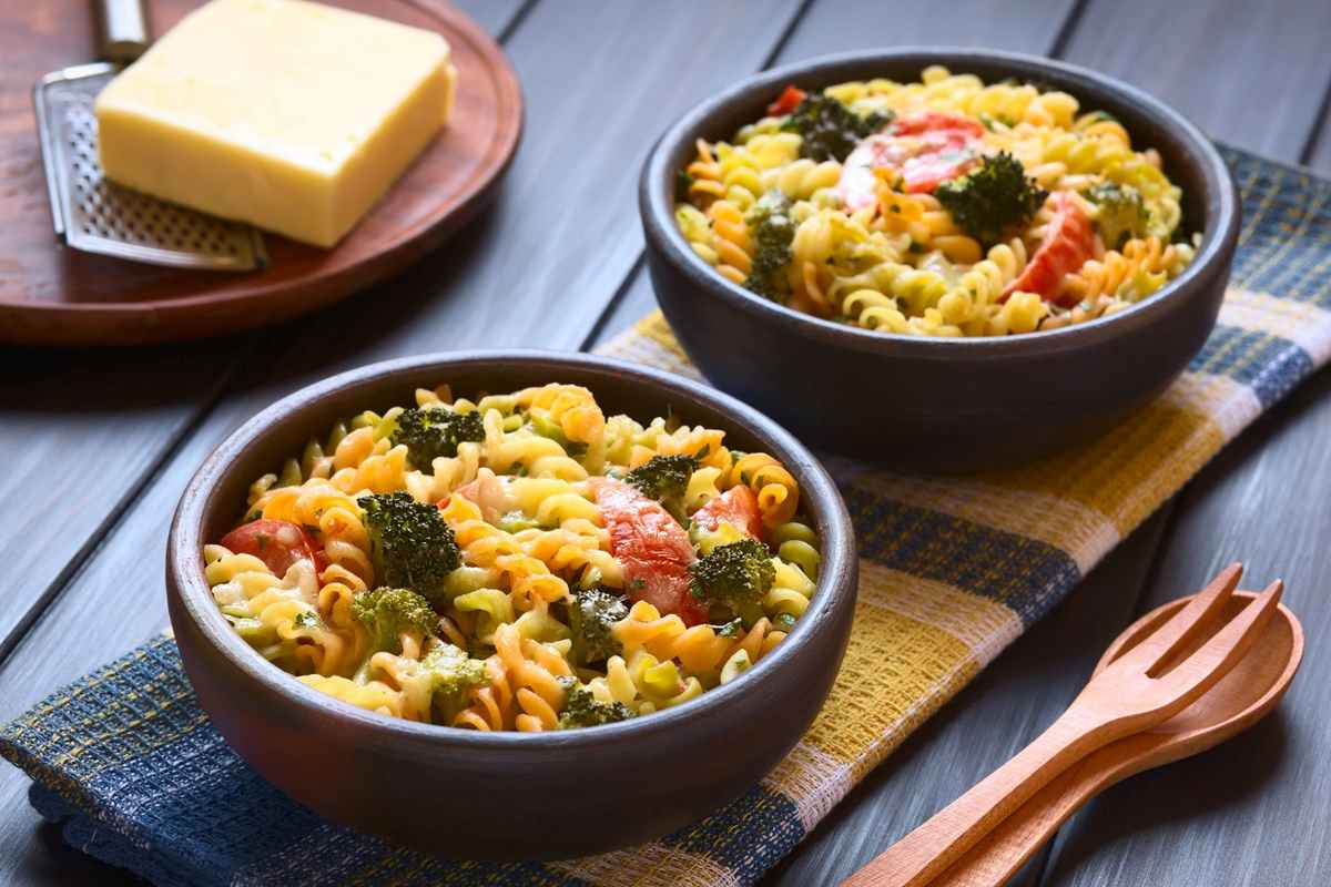 Two bowls of vegetable pasta salad with broccoli and tomatoes, perfect for enjoying the benefits of cooking for one or two people.