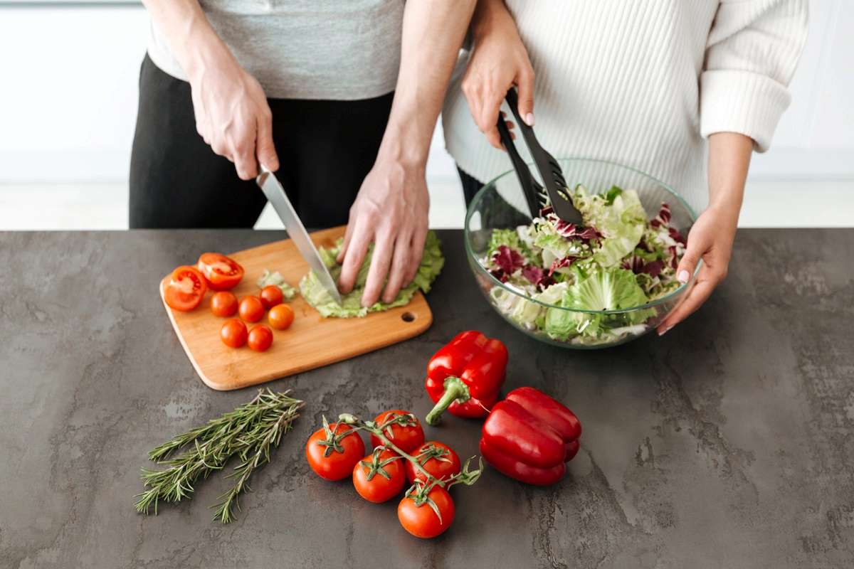 Two people preparing a salad together.