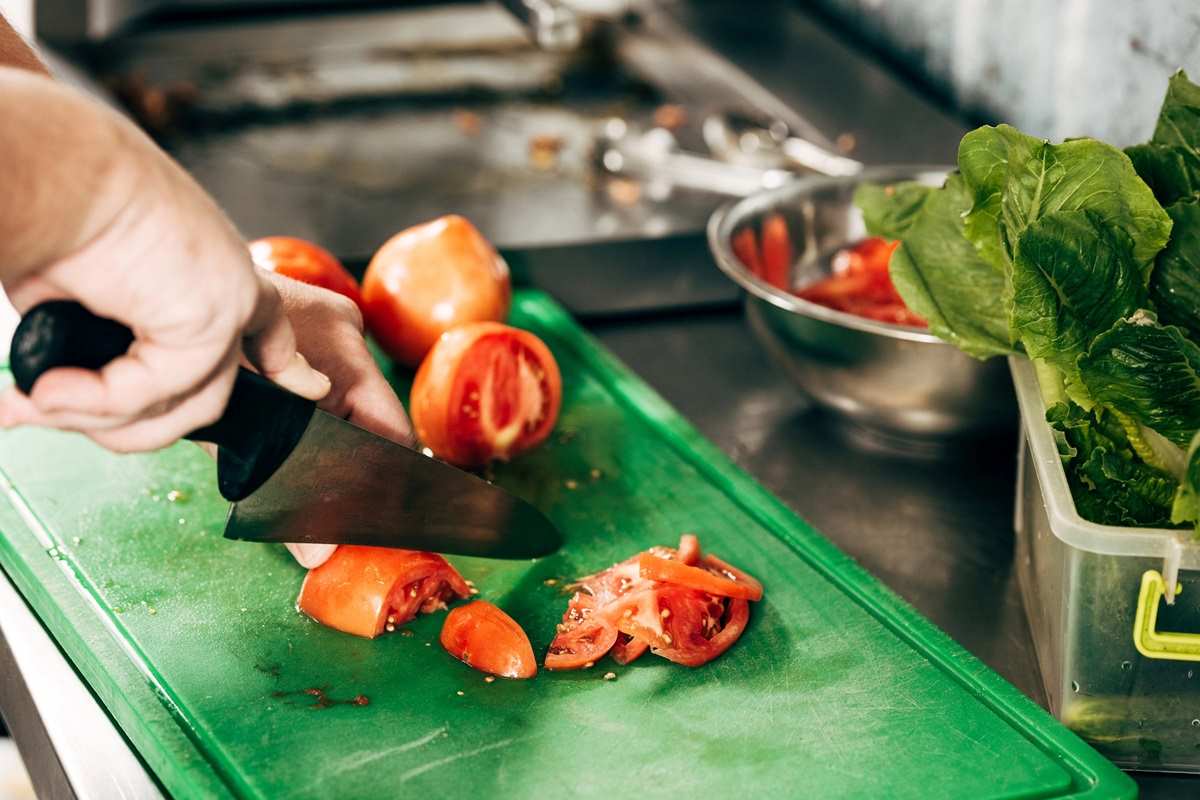 Cutting tomatoes on a green cutting board.