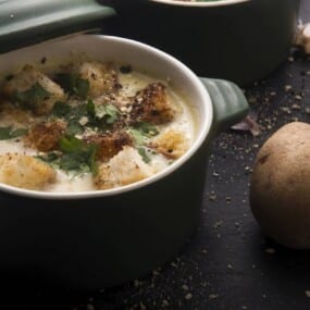 A bowl of garlic soup with potatoes.