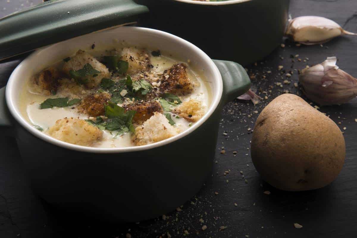 A bowl of garlic soup with potatoes.