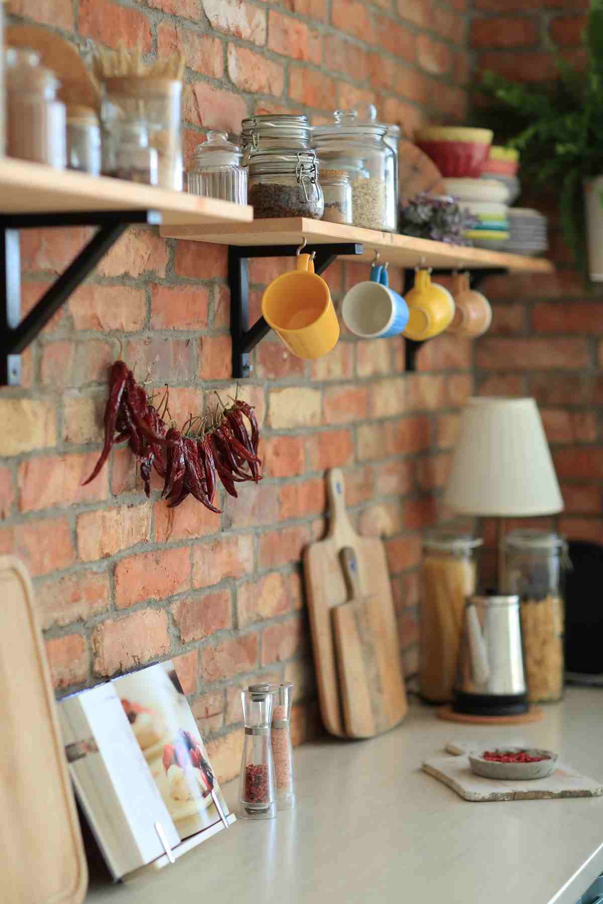 Kitchen with brick wall features shelves holding jars, spices, and mugs.