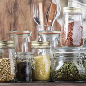 Assorted herbs, grains, and seeds are stored in various glass jars.