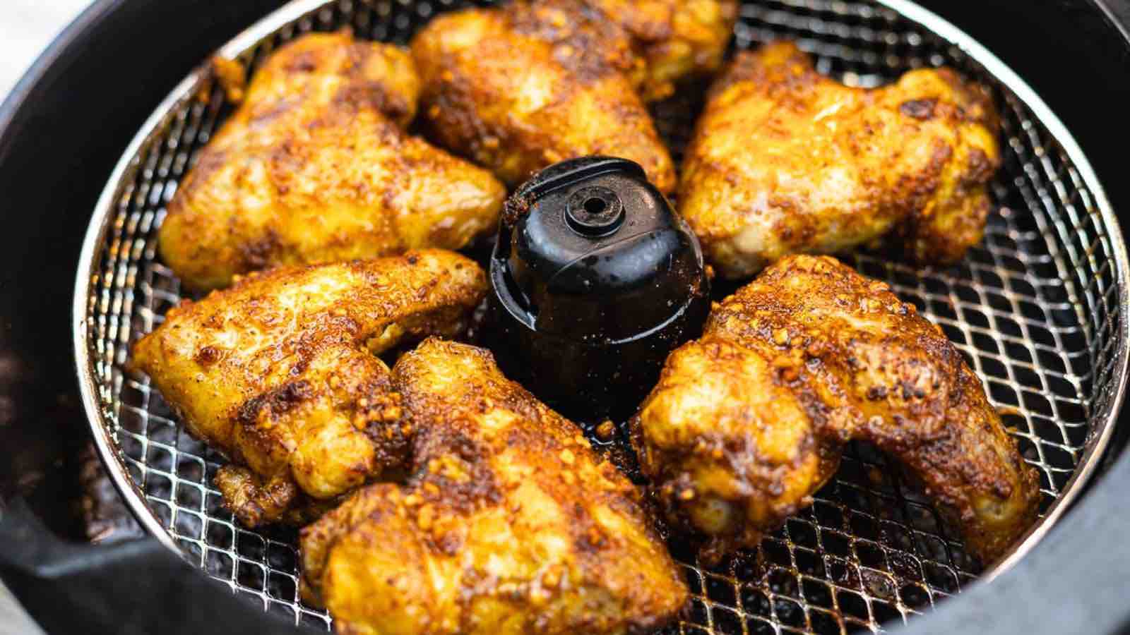 Celebrate game day with an air fryer full of seasoned chicken wings on a metal rack, cooked to a tempting golden brown.