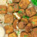Breaded and fried tofu cubes garnished with chopped herbs, served with dipping sauces on the side.