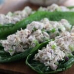Chicken salad with chopped vegetables served on romaine lettuce leaves, arranged on a wooden surface.