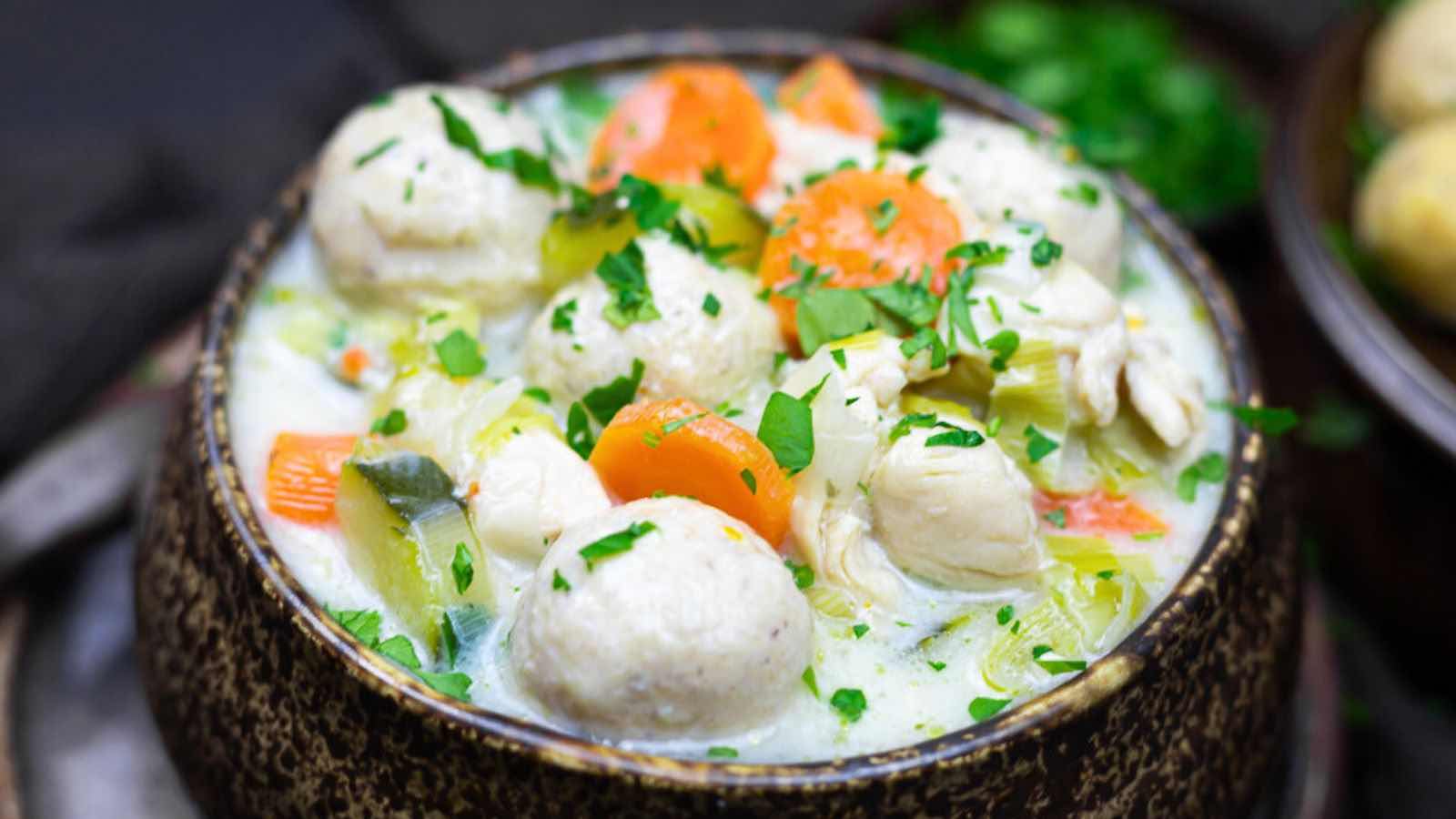 A bowl of creamy chicken and vegetable stew with dumplings, garnished with chopped parsley—chicken meals keep my weeknight cozy and satisfying.