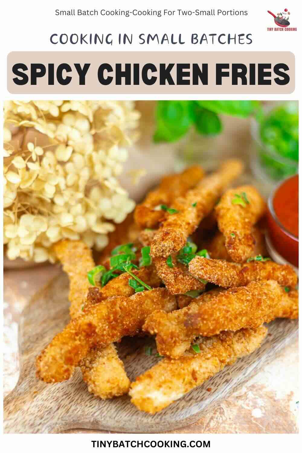 A wooden board topped with several crispy, breaded spicy chicken fries garnished with fresh herbs, with a dried flower and a small bowl of dipping sauce in the background.