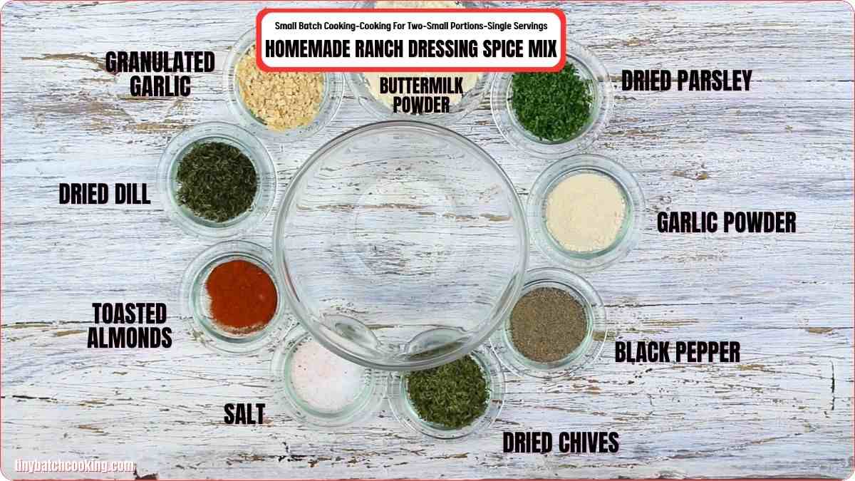 A glass bowl is surrounded by small bowls of spices and ingredients labeled for homemade ranch dressing spice mix, including dill, chives, garlic, parsley, and buttermilk powder.