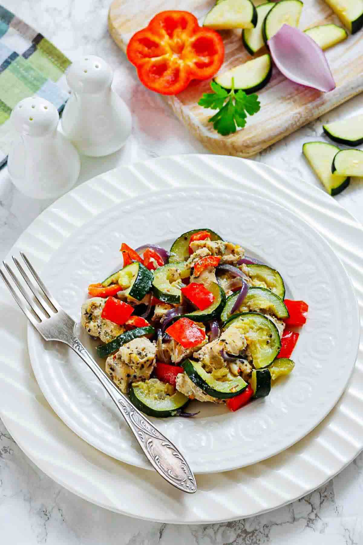 Chicken and vegetables plated with serving fork.