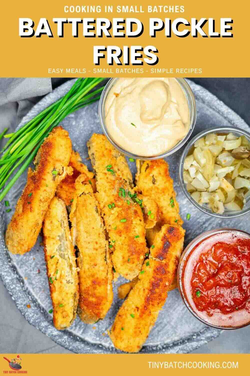 A plate of battered pickle fries served with three dipping sauces, garnished with chopped chives, displayed on a gray plate.