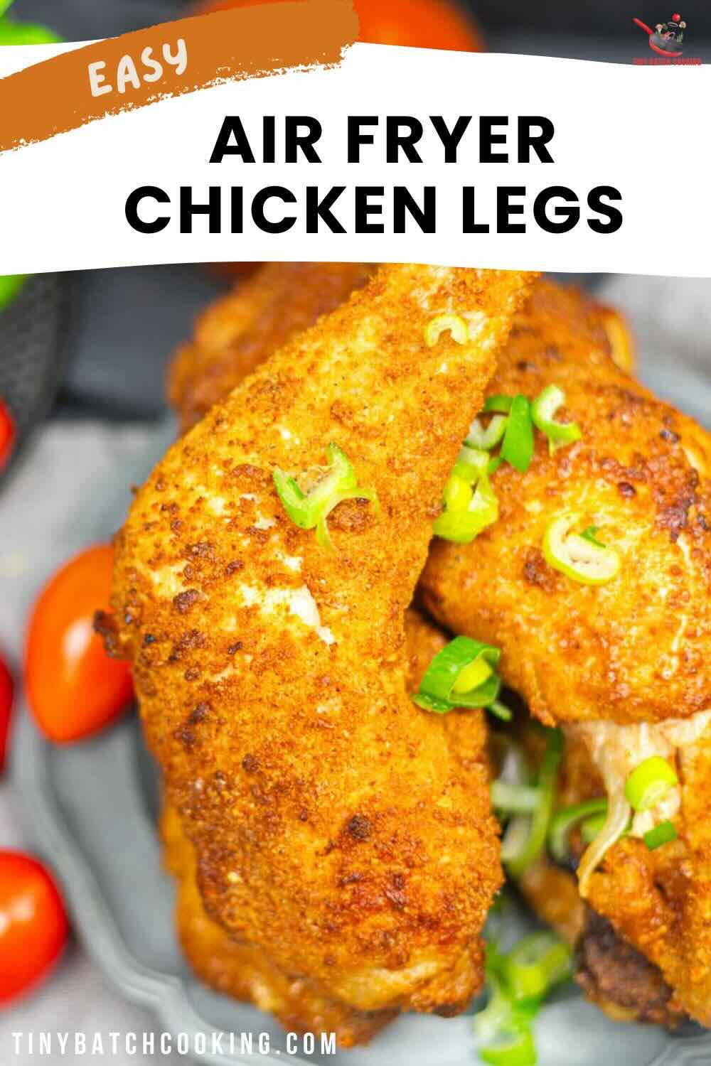 Close-up of air-fried chicken legs garnished with chopped green onions, served on a plate with cherry tomatoes. Text overlay reads "Easy Air Fryer Chicken Legs.