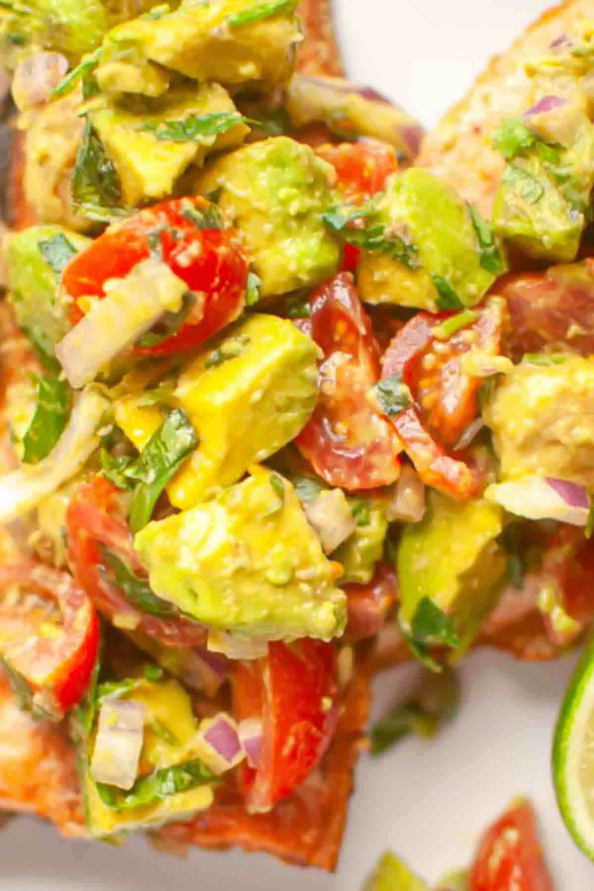 Chopped avocado, cherry tomatoes, red onion, and herbs mixed together and served on a slice of bread.