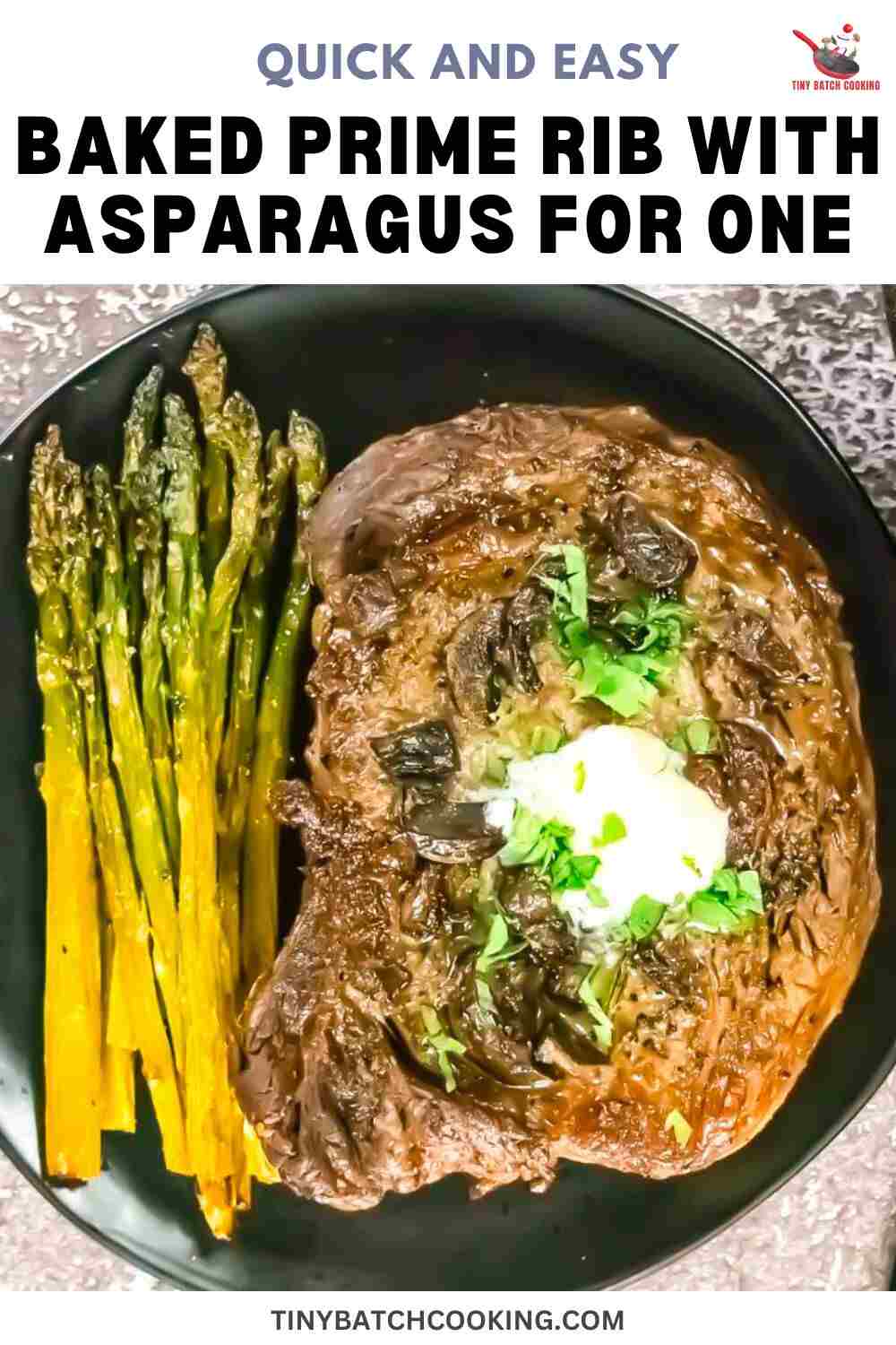 A cooked prime rib steak with mushrooms, herbs, and butter is served on a black plate with roasted asparagus.