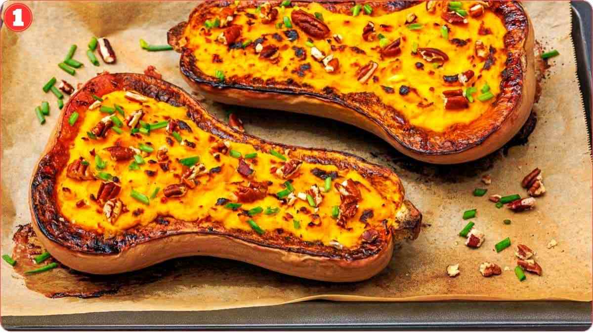 Two halves of baked stuffed butternut squash topped with chopped pecans and chives on a parchment-lined baking tray.