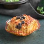 Zucchini muffin topped with chocolate chips in a paper liner.