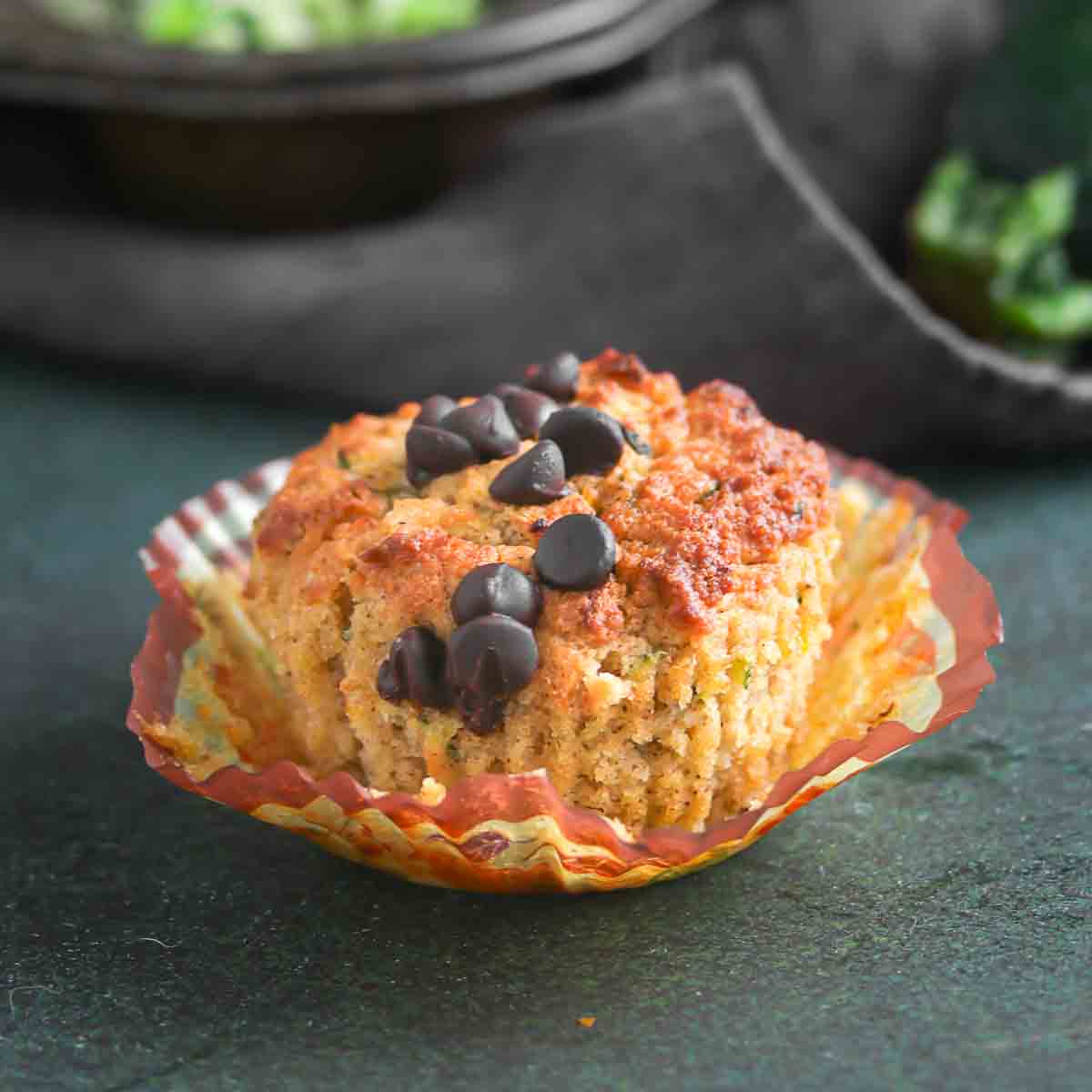 Zucchini muffin topped with chocolate chips in a paper liner.